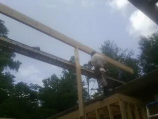 Carpenter setting a ridge beam over a new addition frame — Ice Dam Removal by Roofing Brothers in Emington