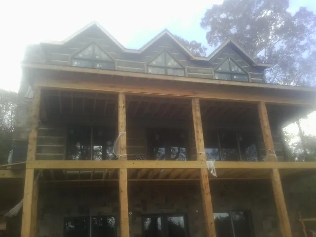 Dormers and porch framing on a large log home under construction — Roof Coating work by our crew in Emington