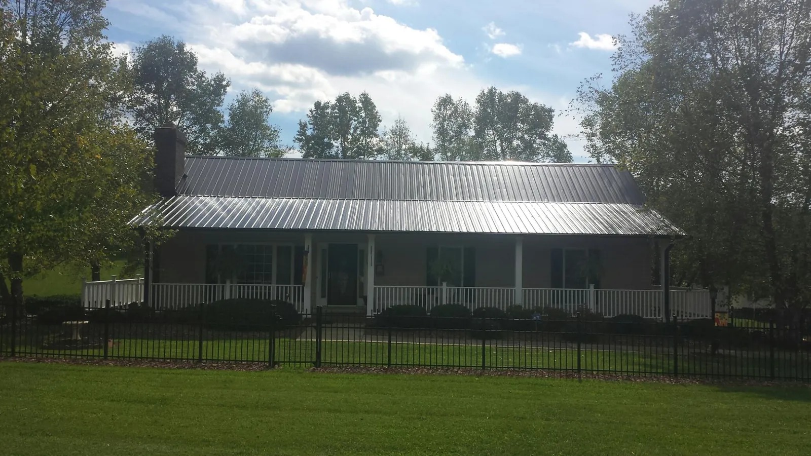 Gray metal roof on a brick ranch with a full width front porch — Gutter Guard Installation work by our crew in Emington