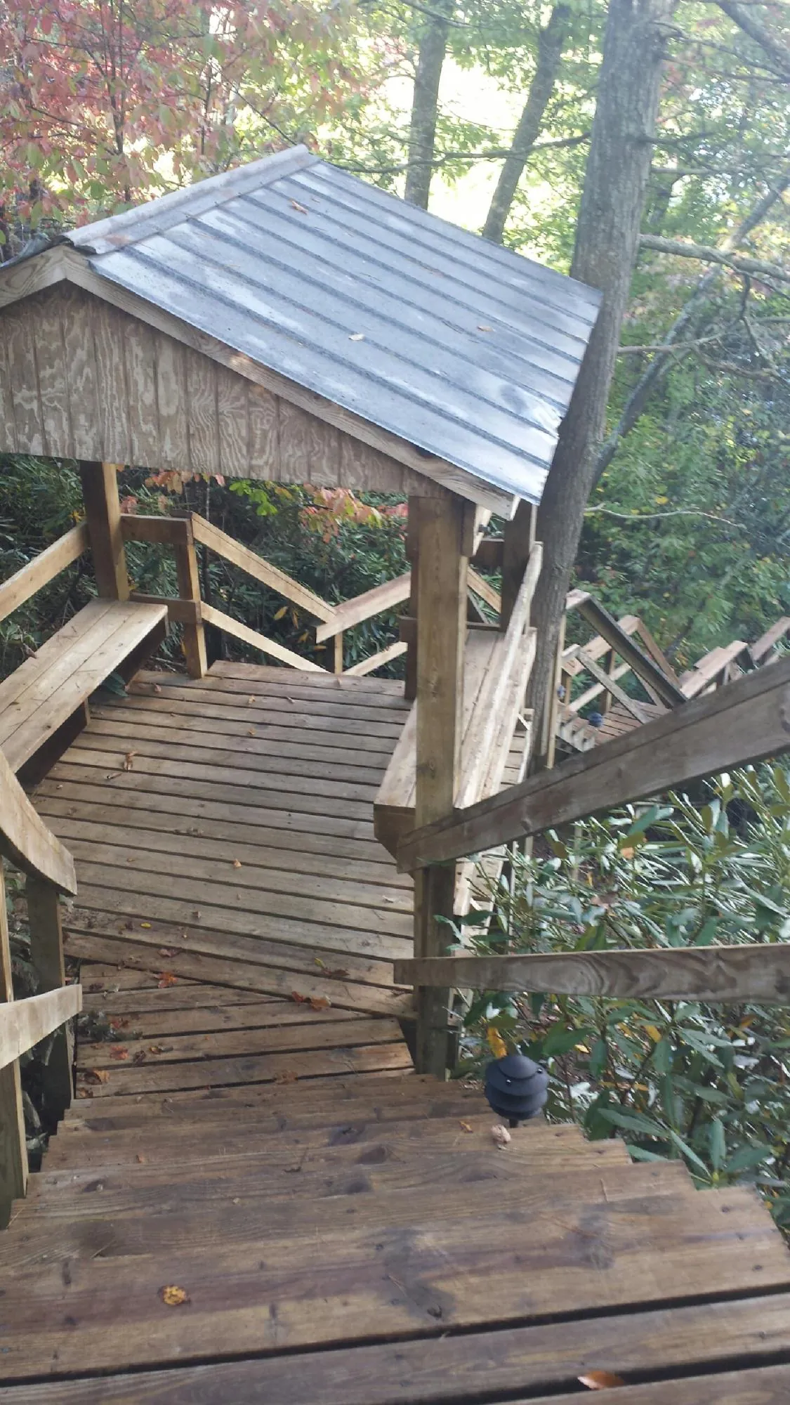 Metal roofed shelter over wooden steps on a wooded walkway — Skylight Repair & Installation work by our crew in Emington