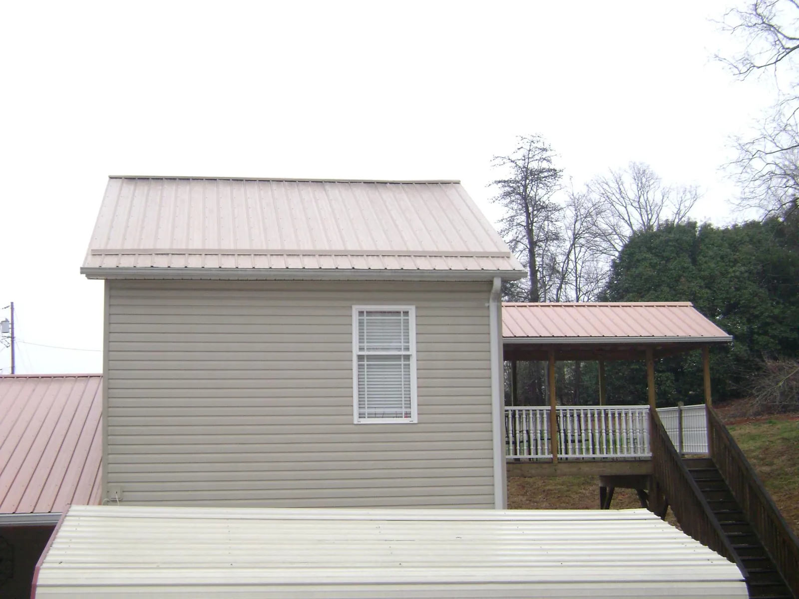 Tan metal roofs on a two story addition and attached porch, from a Roof Replacement job in Emington