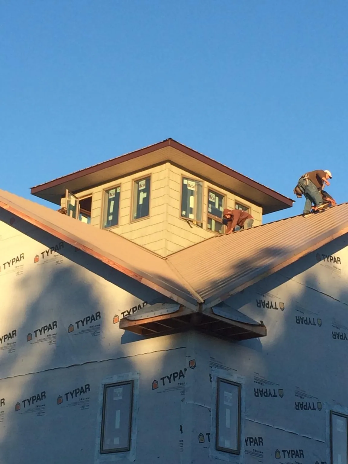 Roofers working around a rooftop cupola on a new metal roof at sunset — Roof Waterproofing in Emington by Roofing Brothers